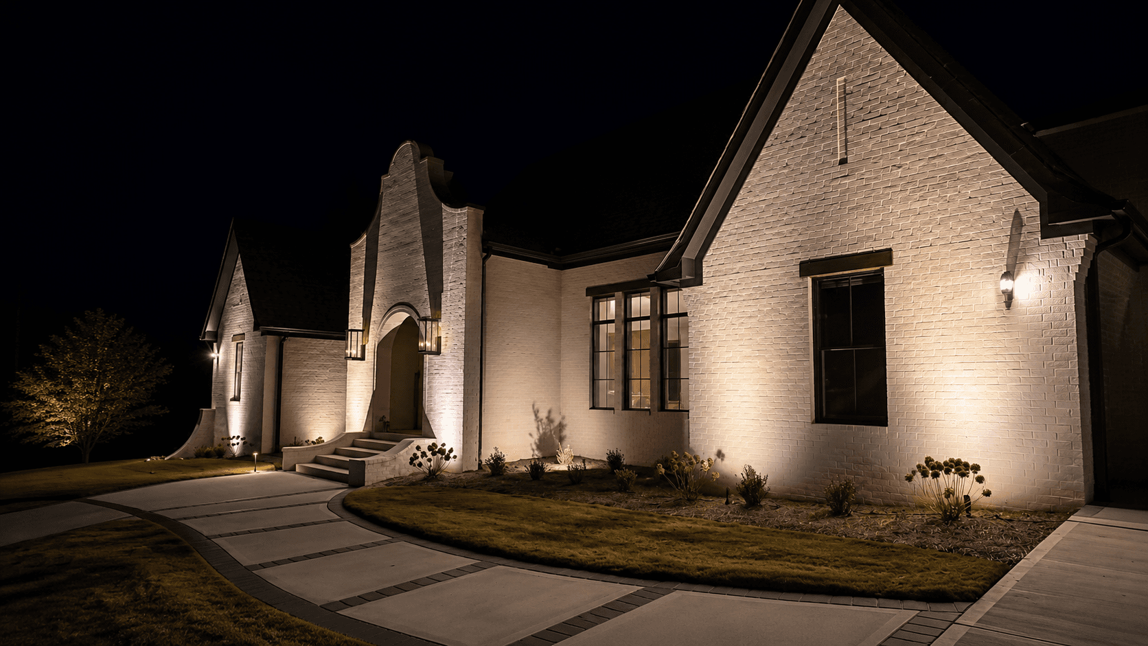 Architectural and landscape lighting on a white brick home