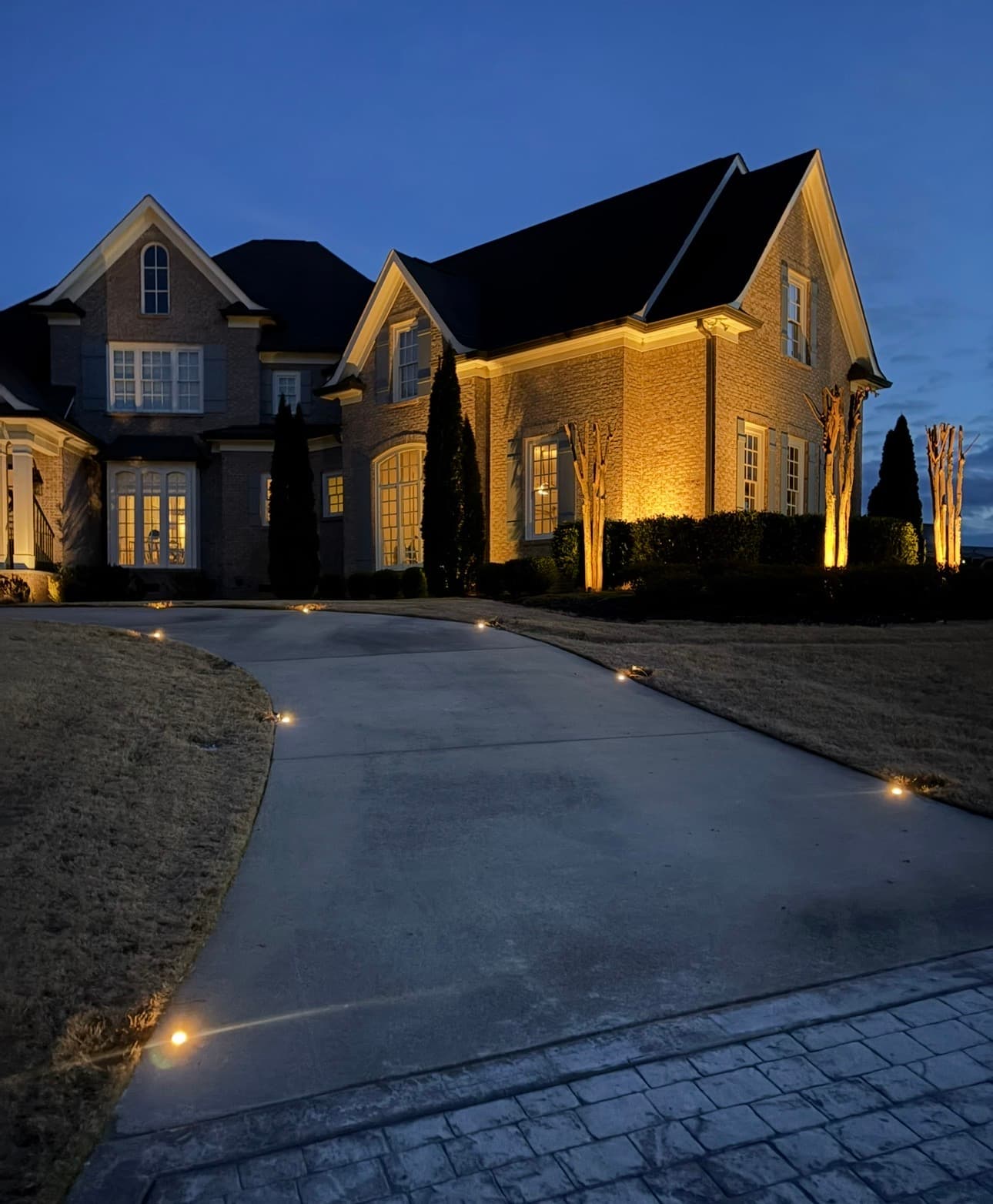 Warm landscape lighting illuminating a large home at night